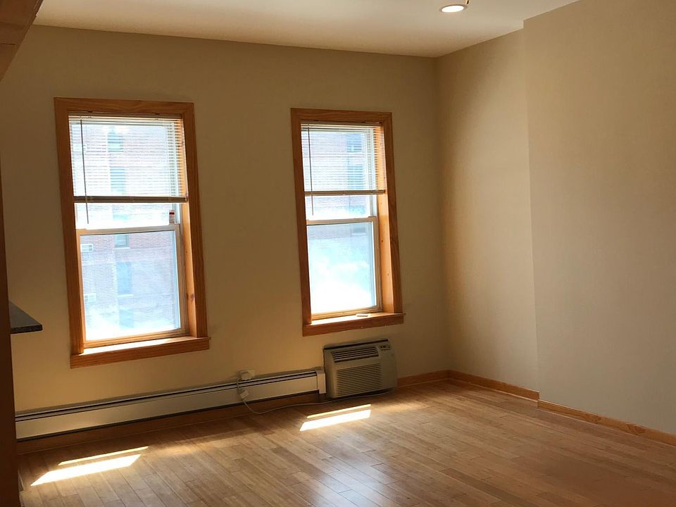 Living room windows, A/C unit, ceiling fan, new windows with new wood casings, hardwood floors and recessed lighting.