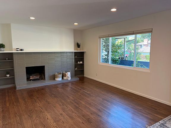 Living room with recessed lights, large windows and top down-bottom up blinds. Wood burning fireplace closed up for heat loss.