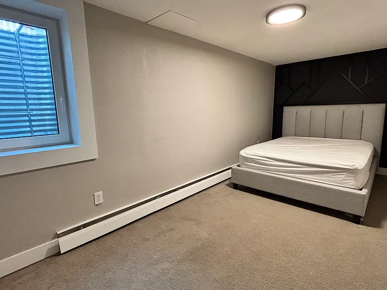First bedroom. Well-lit area with wall-to-wall closet and modern decor.