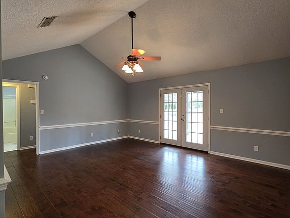 living room with vaulted ceiling and French doors to the fenced back yard