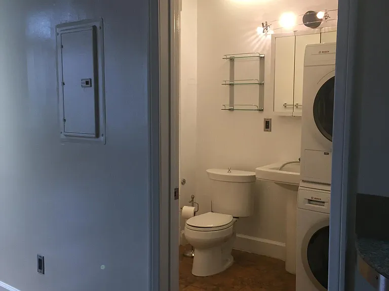 The restroom has a shower, jacuzzi size tub, small shelves and a medicine cabinet over the pedestal sink
