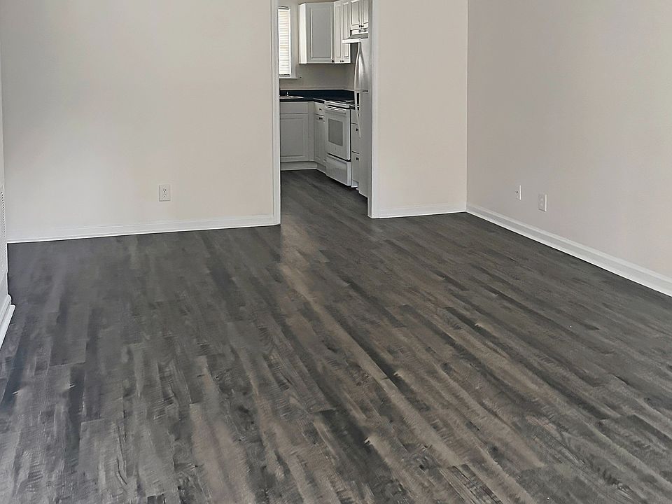 Spacious living area with modern dark wood flooring leading to a sleek kitchen, perfect for family gatherings. Spacious living area with modern dark wood flooring leading to a sleek kitchen, perfect for family gatherings.