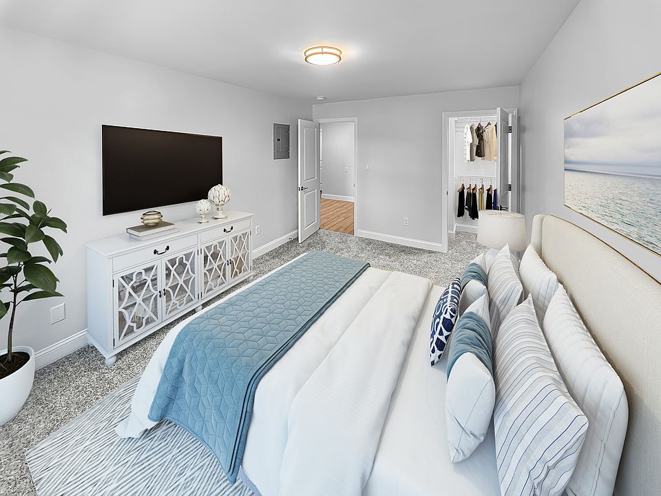 Elegant bedroom with plush carpeting, featuring a luxurious bed with colorful pillows, stylish entertainment console, and a spacious closet.
