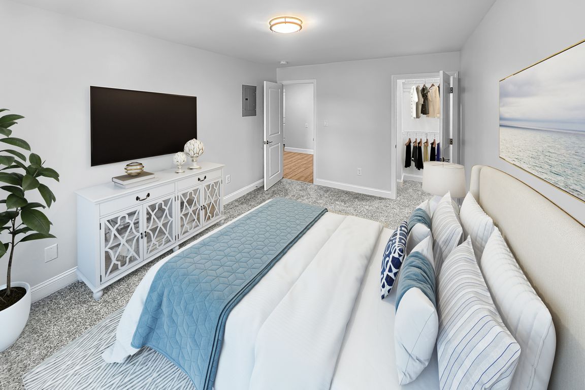 Elegant bedroom with plush carpeting, featuring a luxurious bed with colorful pillows, stylish entertainment console, and a spacious closet.