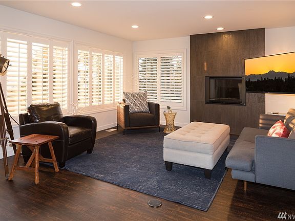 Gorgeous living room with stunning views of the mountains & sound. Gas fireplace, California shutters, low maintenance but high end "wood" looking floors thruout the house.  Tile wall accent around the fireplace.