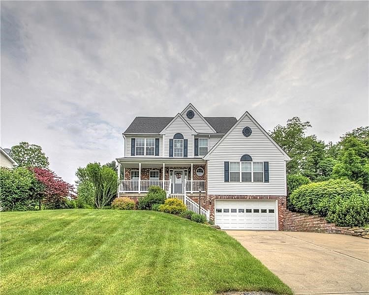 Appealing 2-story brick/vinyl home with colorful landscaping, front porch, and concrete driveway.