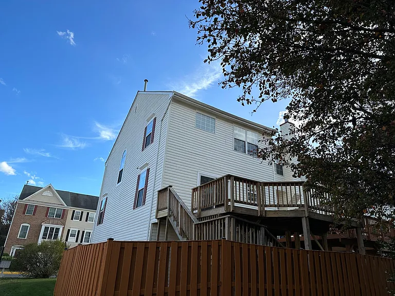 View of the townhouse from the rear common area looking up to the upper deck - back yard is fully fenced in