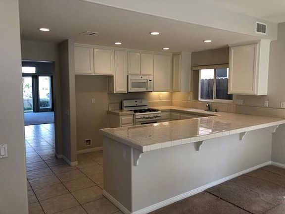 Kitchen. Plenty of cupboard space. Tile flooring and counters in kitchen. Outside Counter area designed for counter bar stools. Flooring this side of counter, and in living room has been replaced with new lighter color Plank flooring. A must See!