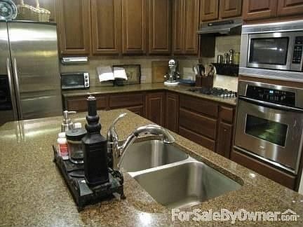 Kitchen
						:
						Granite counters, stainless steel appliances, and hardwood cabinets