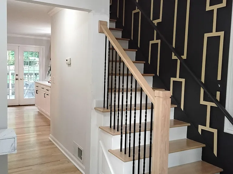 Welcoming entry foyer with hardwood floors, statement accent wall, and a sturdy staircase leading to the upper level.