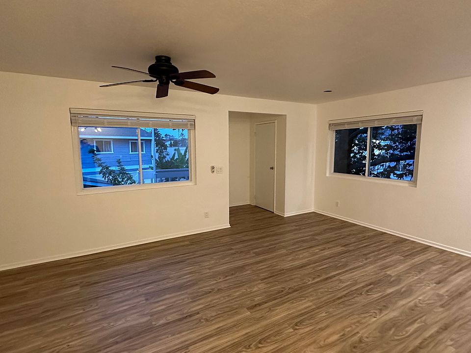 view of living area from kitchen. ceiling fan is remote controlled. large windows throughout. coat closet at entrance of unit. beautiful new 2" faux wood blinds