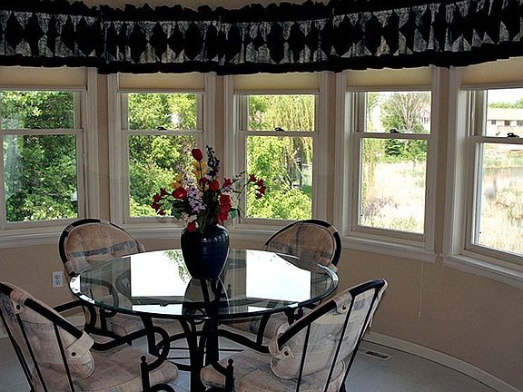 Walls of curved windows highlight views of the pond in this informal Dining Rm