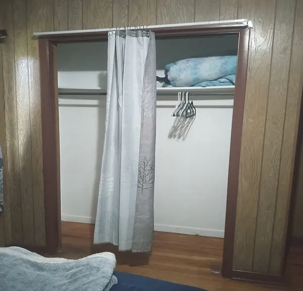 Medium sized closet with hangers, cover, and extra pillow cases.