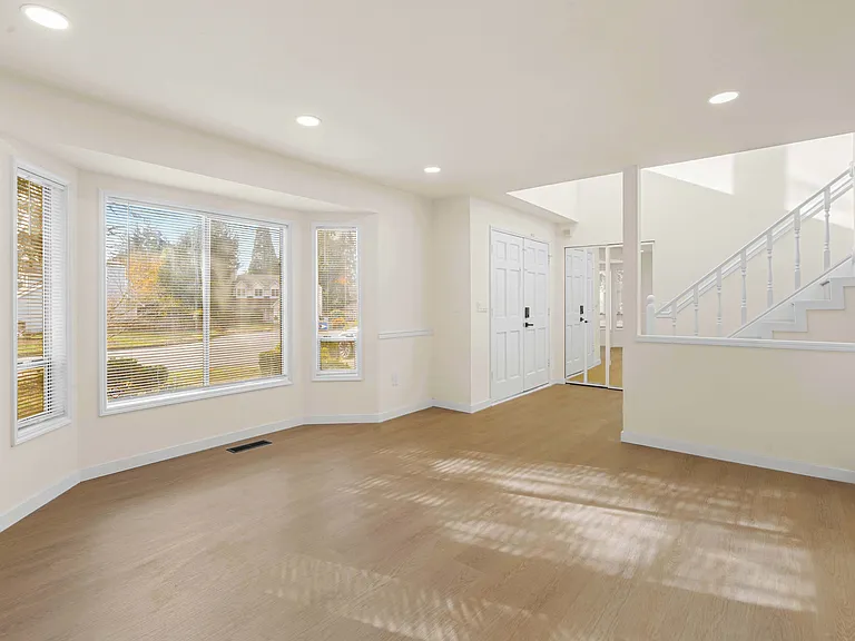 Bright living room with large windows overlooking the beautifully landscaped front yard.