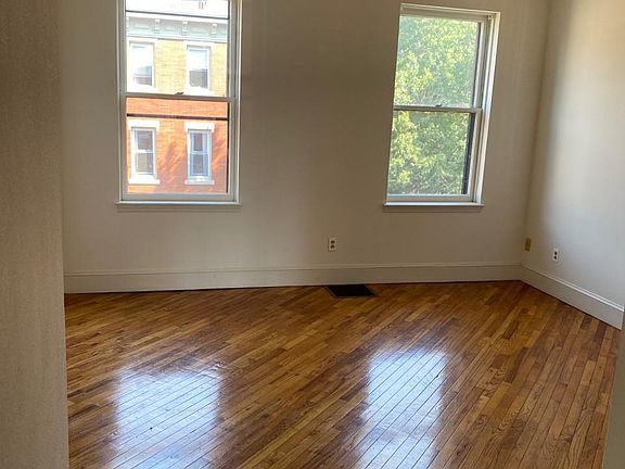 Second bedroom two windows with storms and a screen. ceiling fan with light source, hardwood floors