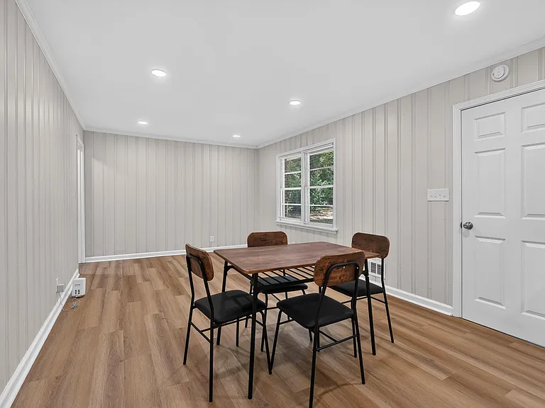 Dedicated dining area with table seating, recessed lighting, and durable wood-look flooring near a large window.