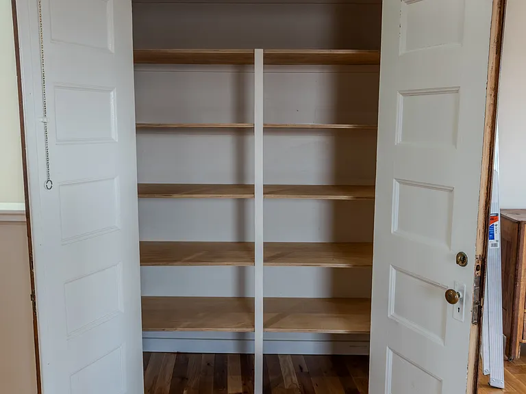 Pantry storage closet with antique wooden doors.