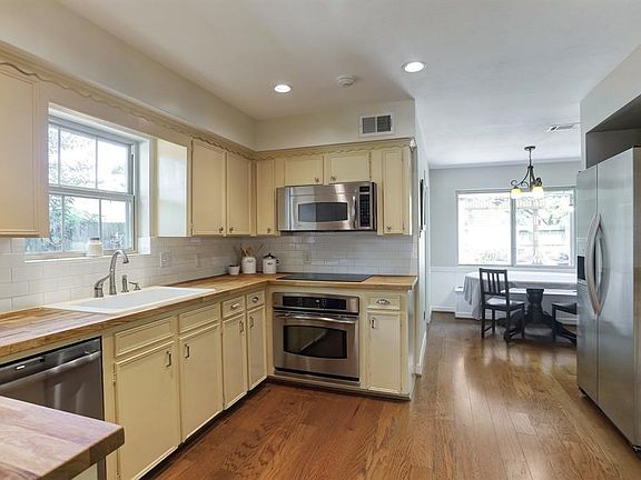 The kitchen is clean and bright, updated with butcher block counters, white subway tile backsplash and recent stainless steel appliances. The kitchen opens to the breakfast area.