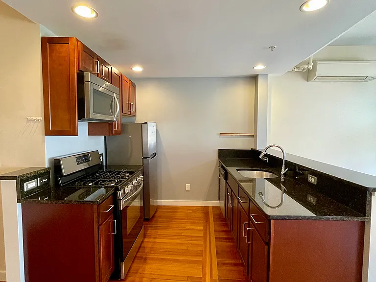 Kitchen space with dishwasher, five-burner propane stove, microwave and dark granite countertops.