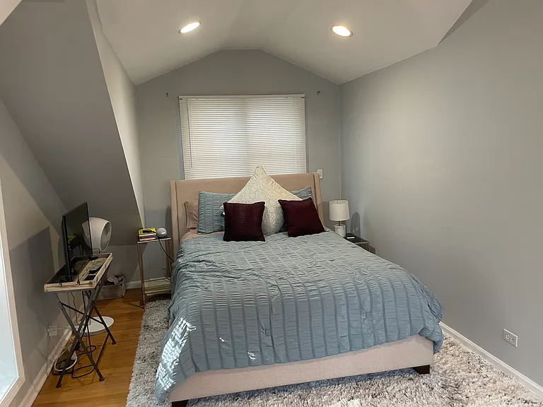Oversized primary suite with vaulted ceilings, abundant natural light, an en-suite bathroom, and a walk-in closet featuring custom ELFA shelving.