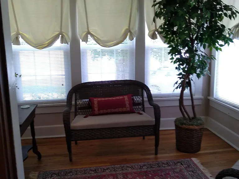Bright sunroom with wicker furniture.