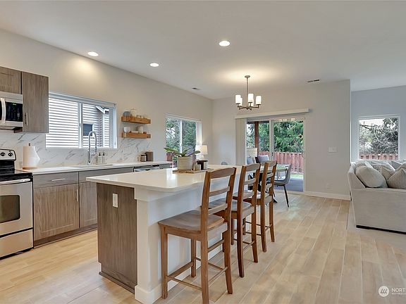 The chef's kitchen features quartz counter tops, updated cabinetry & island seating.>