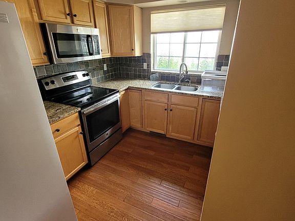 Fully appointed kitchen with granite countertops, range, refrigerator and microwave.