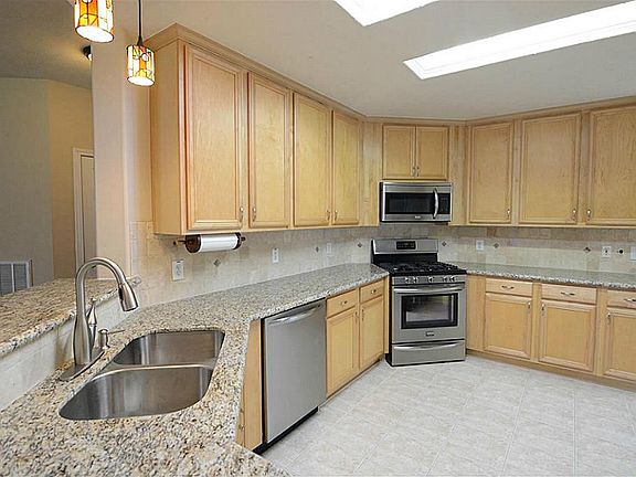 Stainless steel appliances, granite counters, and tile floors.