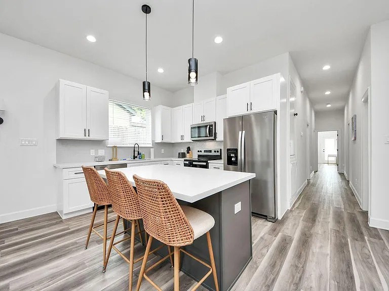 Open kitchen with a large island for seating, ample white cabinetry, and stainless-steel appliances for everyday cooking.
