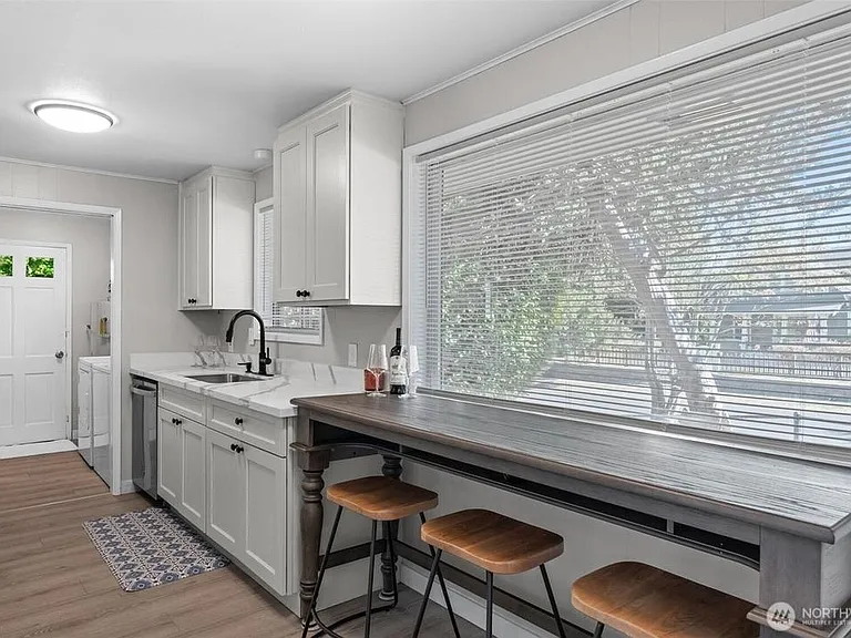 Kitchen with ample cabinetry, dishwasher, and a long window-side breakfast bar for convenient everyday dining.