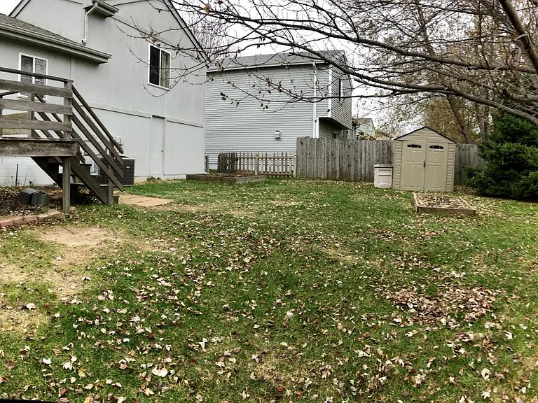 Fully fenced backyard with garden box and storage shed.