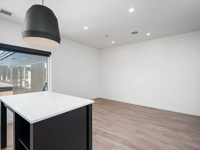 Modern open-concept living space with elegant pendant lighting, large windows providing natural light, and sleek wooden flooring. Modern open-concept living space with elegant pendant lighting, large windows providing natural light, and sleek wooden floor
