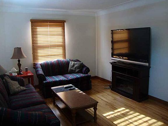 Living room with wood blinds on the windows.