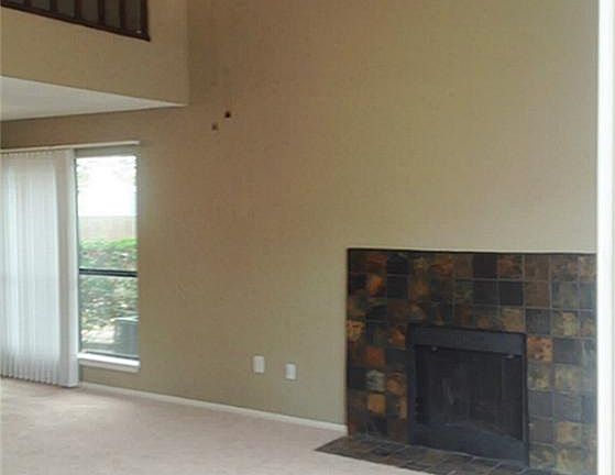 Large two story living room features vaulted ceilings, upgraded fan/light fixture, and a wood burnin