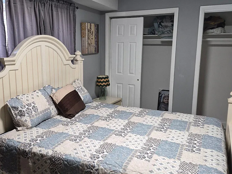 Furnished bedroom with a full bed, nightstand, and window with curtains, plus closet storage for easy organization.