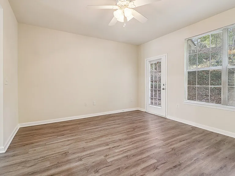 Bright and airy room with sleek hardwood floors, a ceiling fan, and large windows offering scenic views.