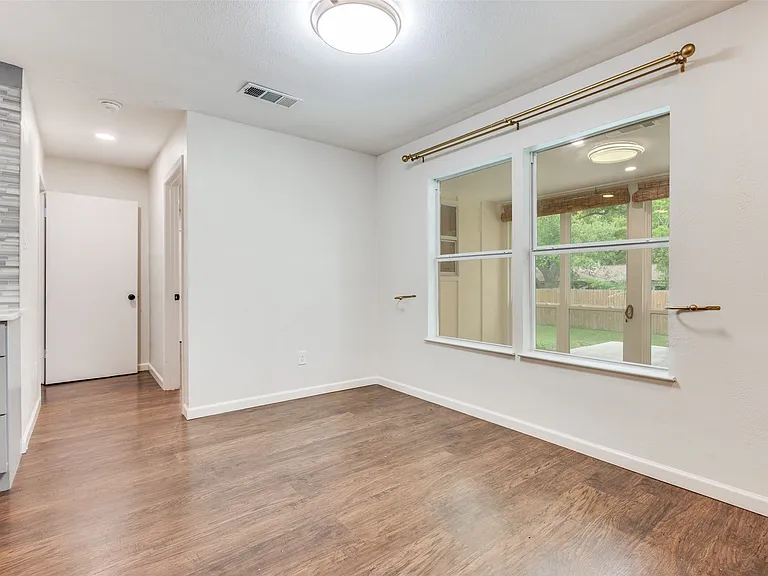 Dining area featuring wood-finish flooring, a double window overlooking the backyard, and a modern flush-mount ceiling light