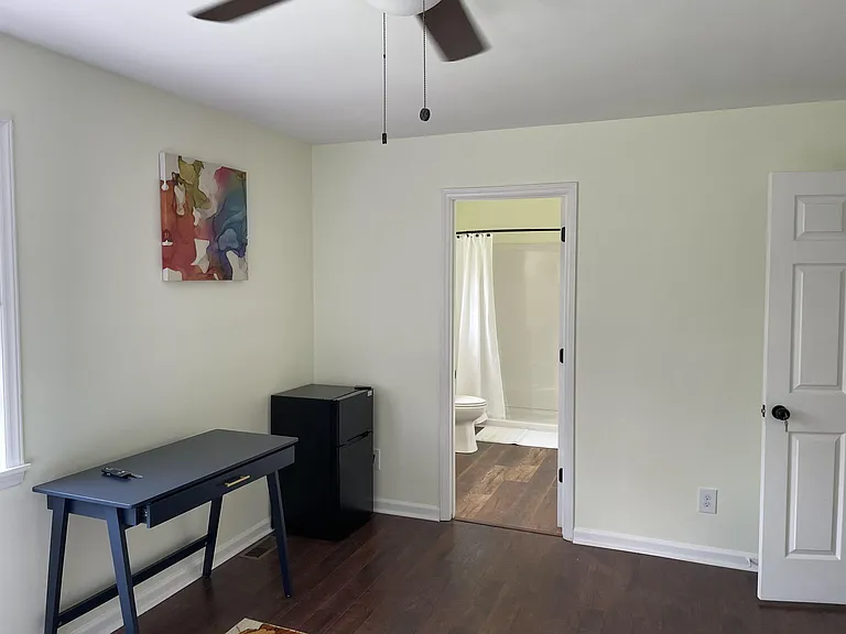 Private bedroom with hardwood floors, ceiling fan, and space for a desk, plus convenient access to a nearby bath.