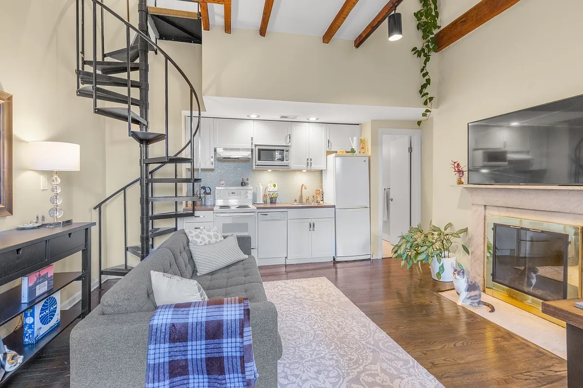 Living room, kitchen, stairs to bedroom, door to restroom, and wood burning fireplace. - 1130 Spruce St #3B