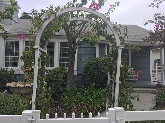 Fenced front garden with serene water fountain feature; porc