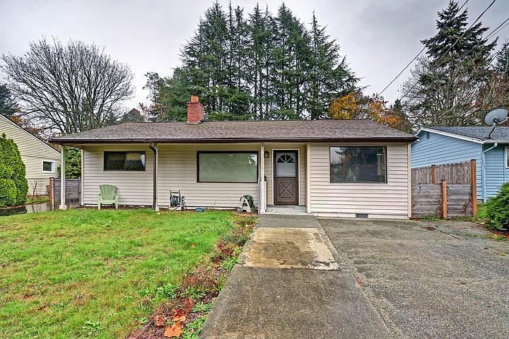 Large front yard with parking pad and driveway to left of the home.