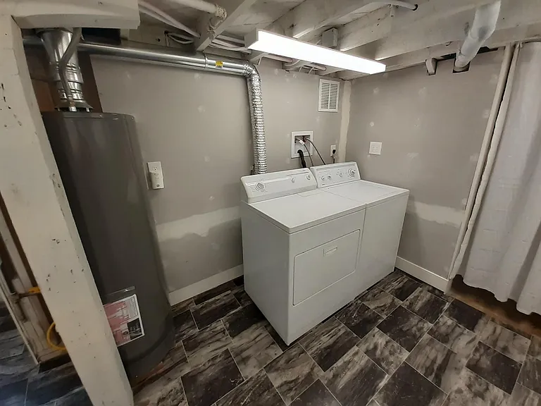 Well-lit basement Laundry room with extra storage.