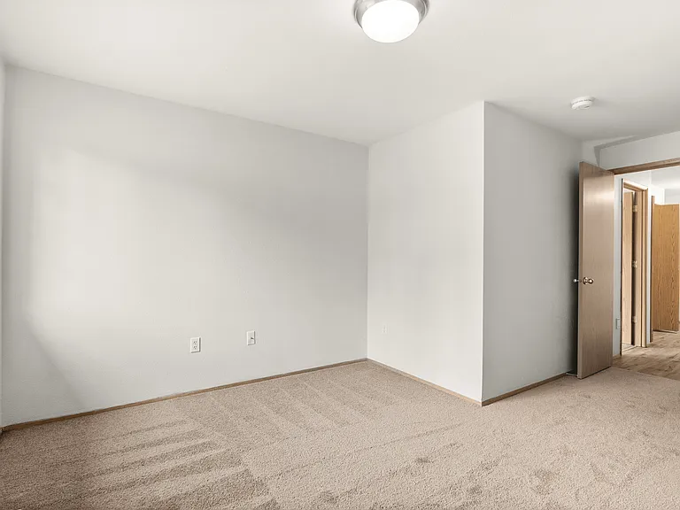 Comfortable bedroom with plush carpeting, natural light, and a simple, open layout. Comfortable bedroom with plush carpeting, natural light, and a simple, open layout.