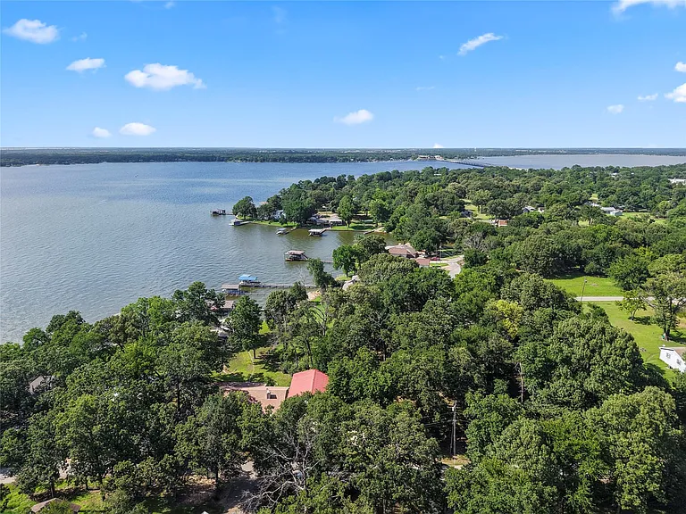 Expansive waterfront property featuring a red-roofed residence amidst mature trees