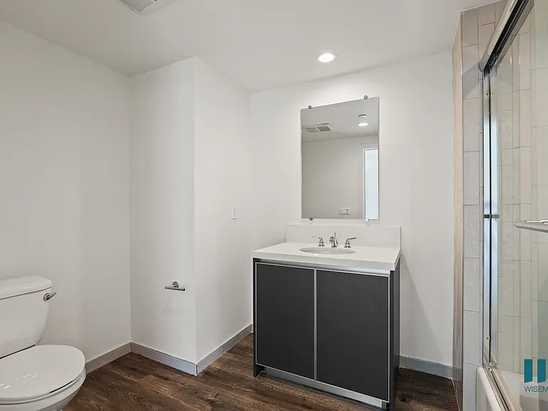 Bathroom with Full-Size Bathtub with Glass Door and Cabinet Storage