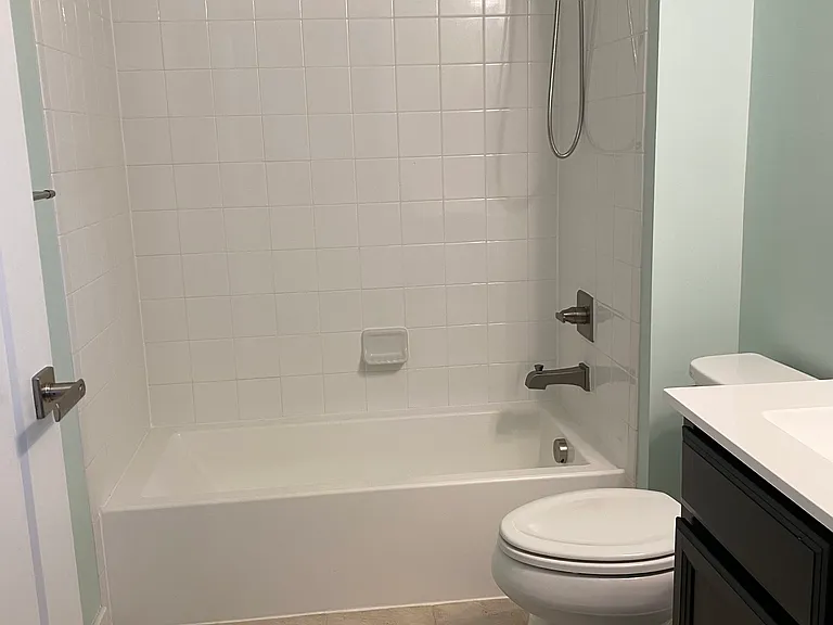 Hallway bathroom with a tub and shower combo. Tiled floor.