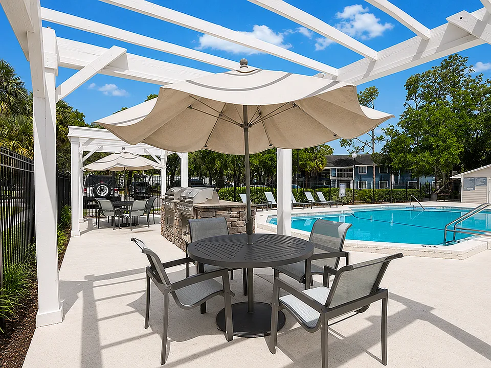 Inviting outdoor space with modern seating, BBQ grill, and sunlit swimming pool, perfect for relaxation.