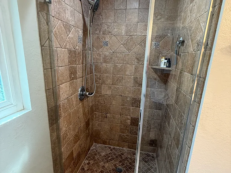 Primary shower with travertine stone.