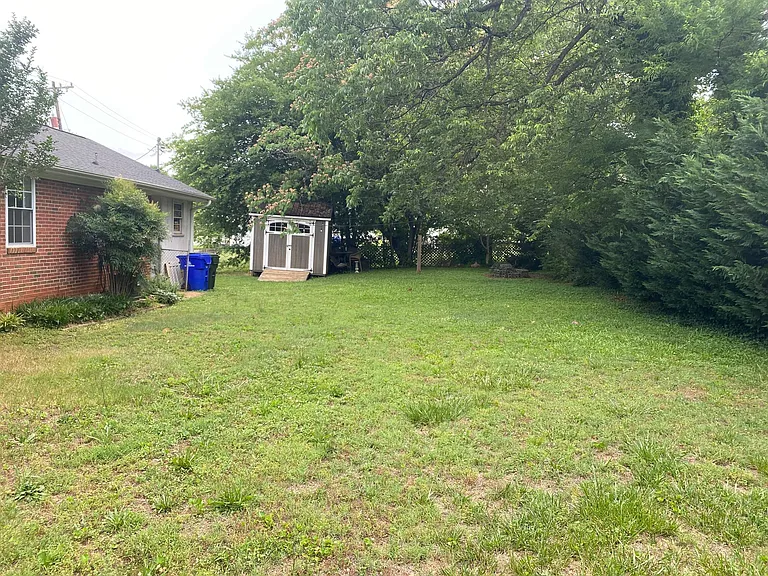 Large private fenced in backyard with fire pit and hanging string lights