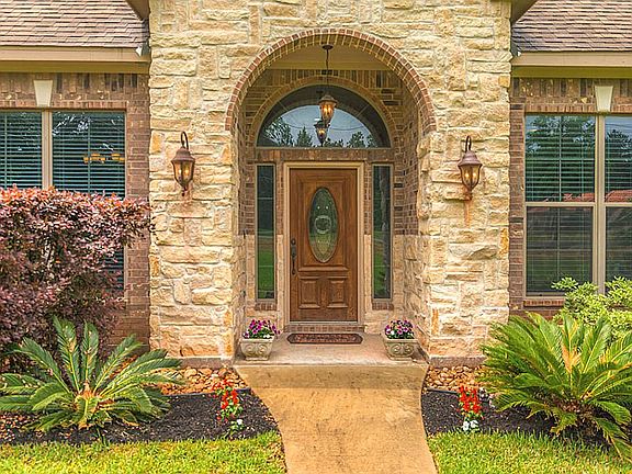 The entry is flanked by stone with oil rubbed bronze lighting sconces on either side. The entry door